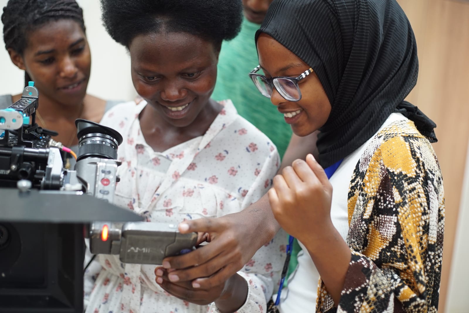 Joyful young Rwandan creators and students with disabilities operating a cinema camera monitor together in Kigali